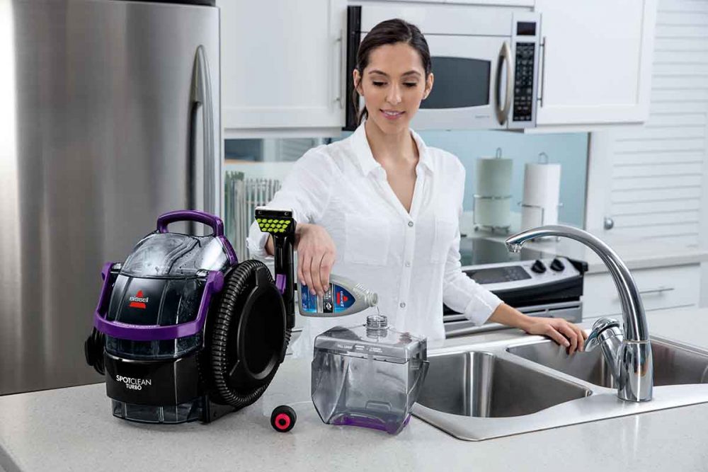 A person filling up the Bissell SpotClean Turbo with Bissell cleaning formula.