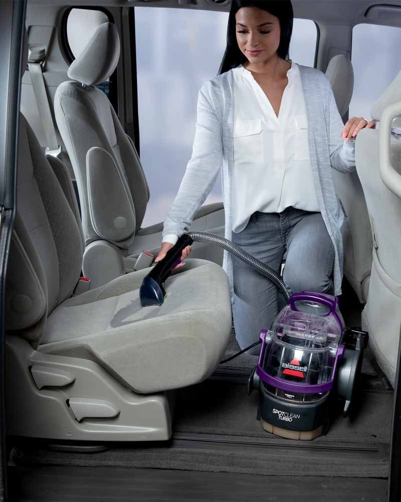 A person cleaning car seats with the Bissell SpotClean Turbo.