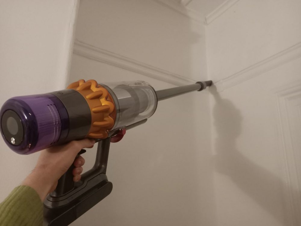 Cleaning a wall with the Dyson V15S Submarine Crevice Tool.