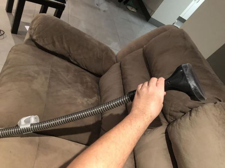 Cleaning a lounge with the Bissell SpotClean Deep Stain tool.