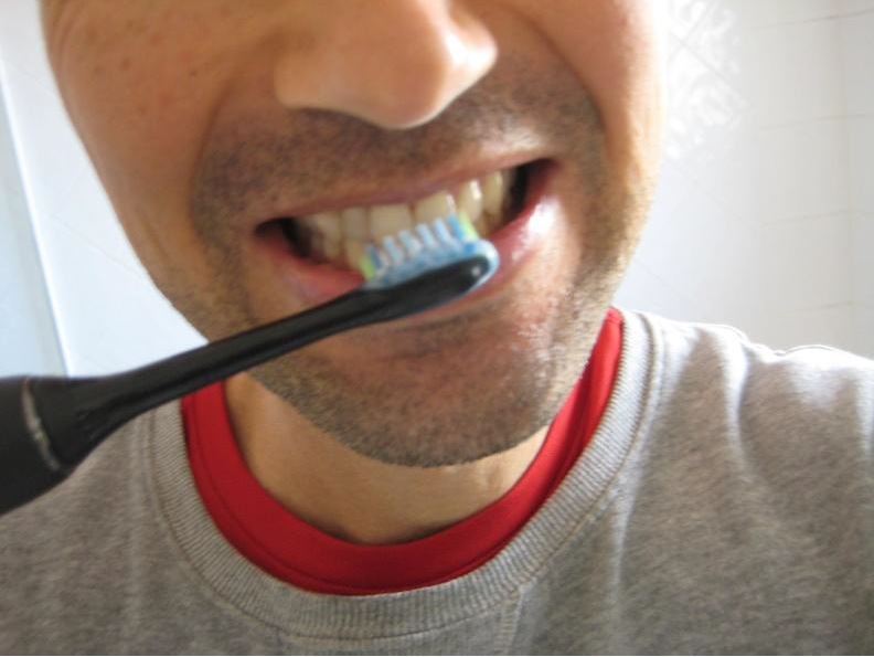 Reviewer using the Philips Sonicare DiamondClean 9000 electric toothbrush to clean his teeth.
