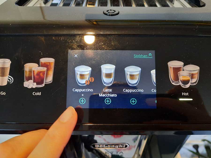 Рецензент выбирает напитки на сенсорном экране кофемашины DeLonghi Eletta Explore.