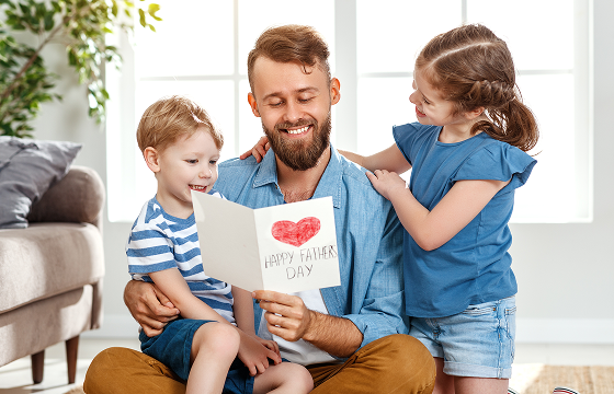Father reading a handmade Father’s Day card with his two children at home 