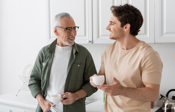 Father and adult son talking over coffee in the kitchen 