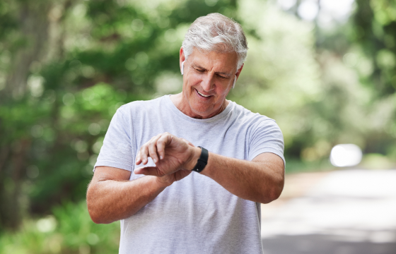 Older man checking his smartwatch while exercising outdoors 