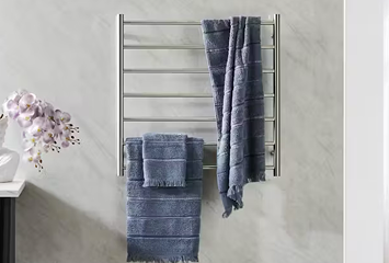 Stainless steel heated towel rail with neatly folded towels in a modern bathroom