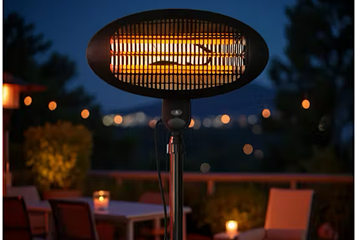 Freestanding outdoor electric heater glowing warmly on a patio at night
