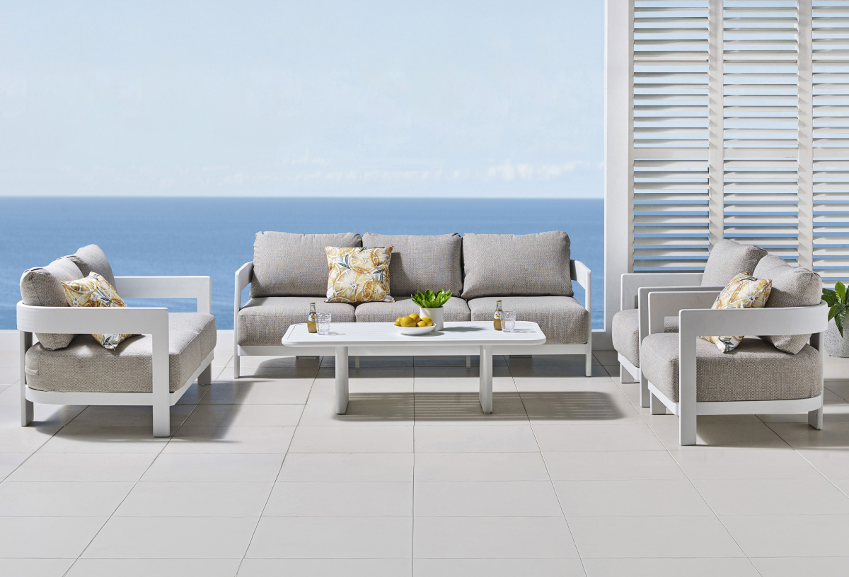 Harvey Norman exclusive Bali 3-seater outdoor sofa with grey cushions, matching armchairs and coffee table on a coastal patio. 