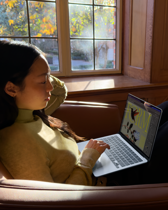 A person sitting in a chair using their MacBook Air