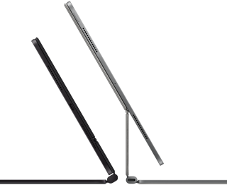 Two iPad Pro devices attached to Magic Keyboard, side exterior, thin profile, space black colour with speakers and USB-C port, tilted half open, silver colour, open, tilted back showing the keyboard’s floating cantilevered design, speakers and microphone